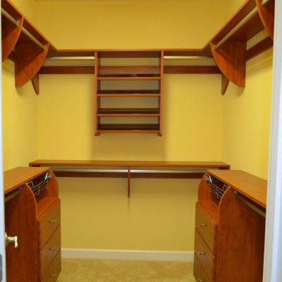 Modest walk-in served by Closet Curves. His and hers drawers, shared angled shoe display, but she gets some long hanging (out of the frame) for dresses.